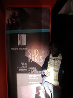 Le sulpteur Eddy Jean Remy (Haiti) devant l'affiche de l'exposition